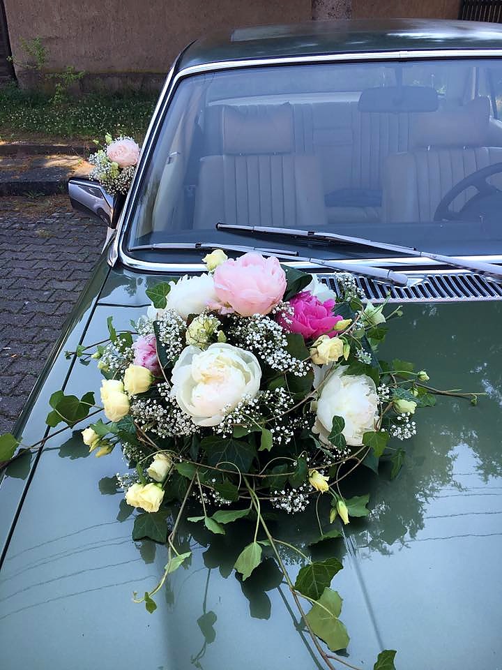 Romantischer Autoschmuck mit Pfingstrosen und Rosen auf einem Brautauto