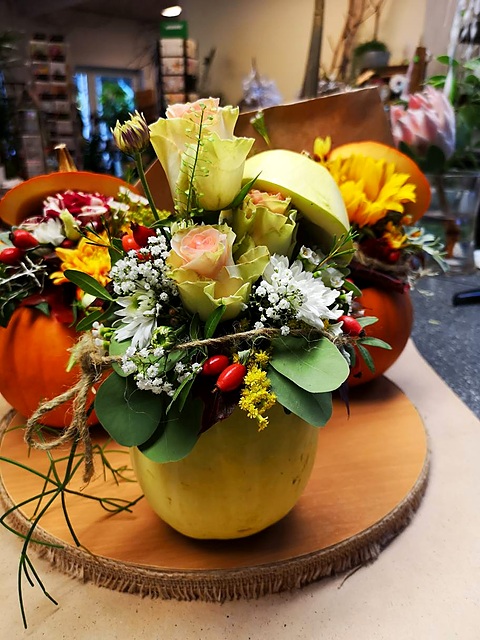 Herbststrauss mit Rosen und Sonnenblume in einem grünen Kürbis