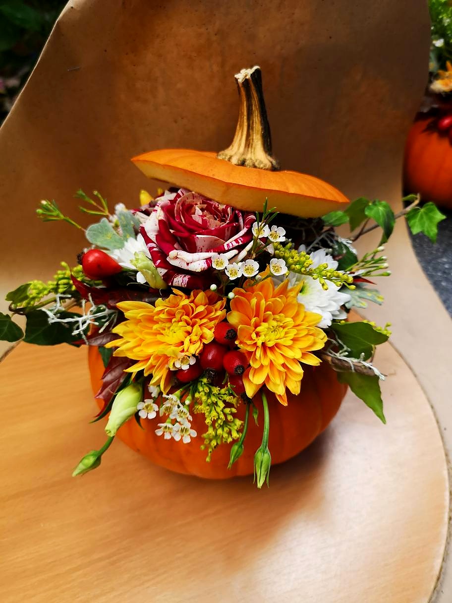 Saisonaler Strauss aus Dahlien, Rosen und Hagebutten in einem Kürbis als Vase – handgebunden im Blumenstudio Jauernek